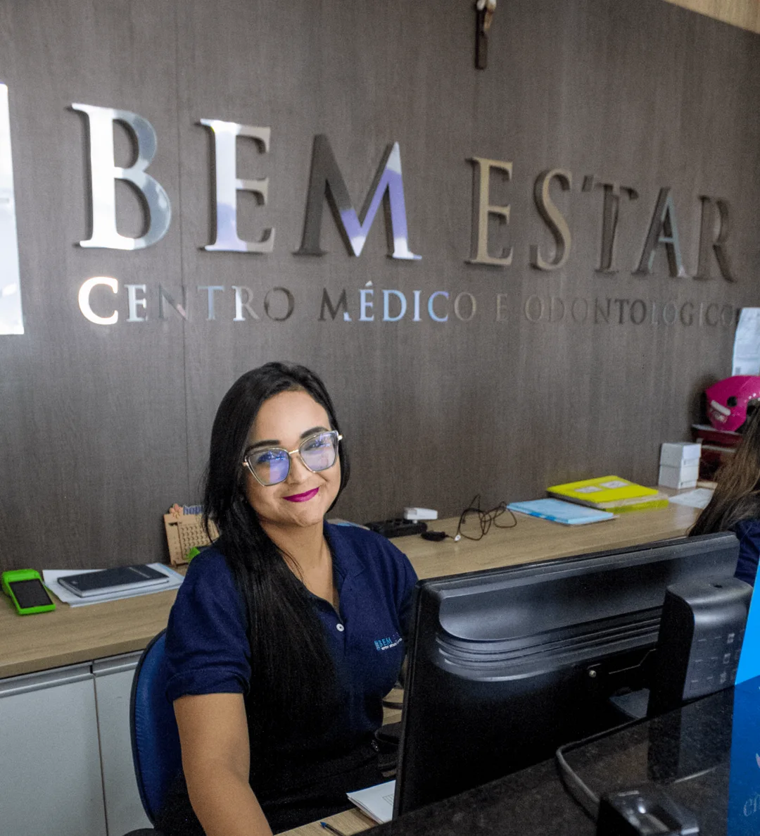 Recepção da Bem Estar, com atendente e a marca da clínica na parede